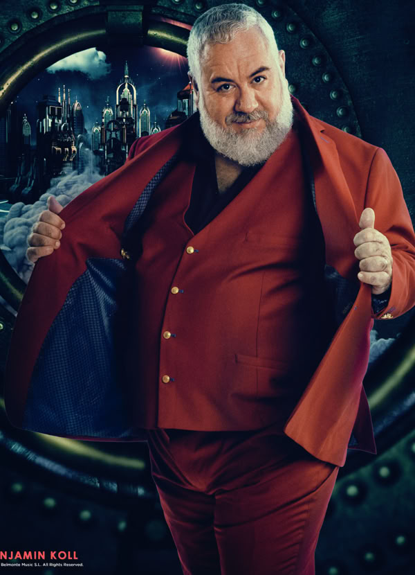 A man with a beard wearing a red suit stands in front of a dark, futuristic background, holding the sides of the suit jacket open.